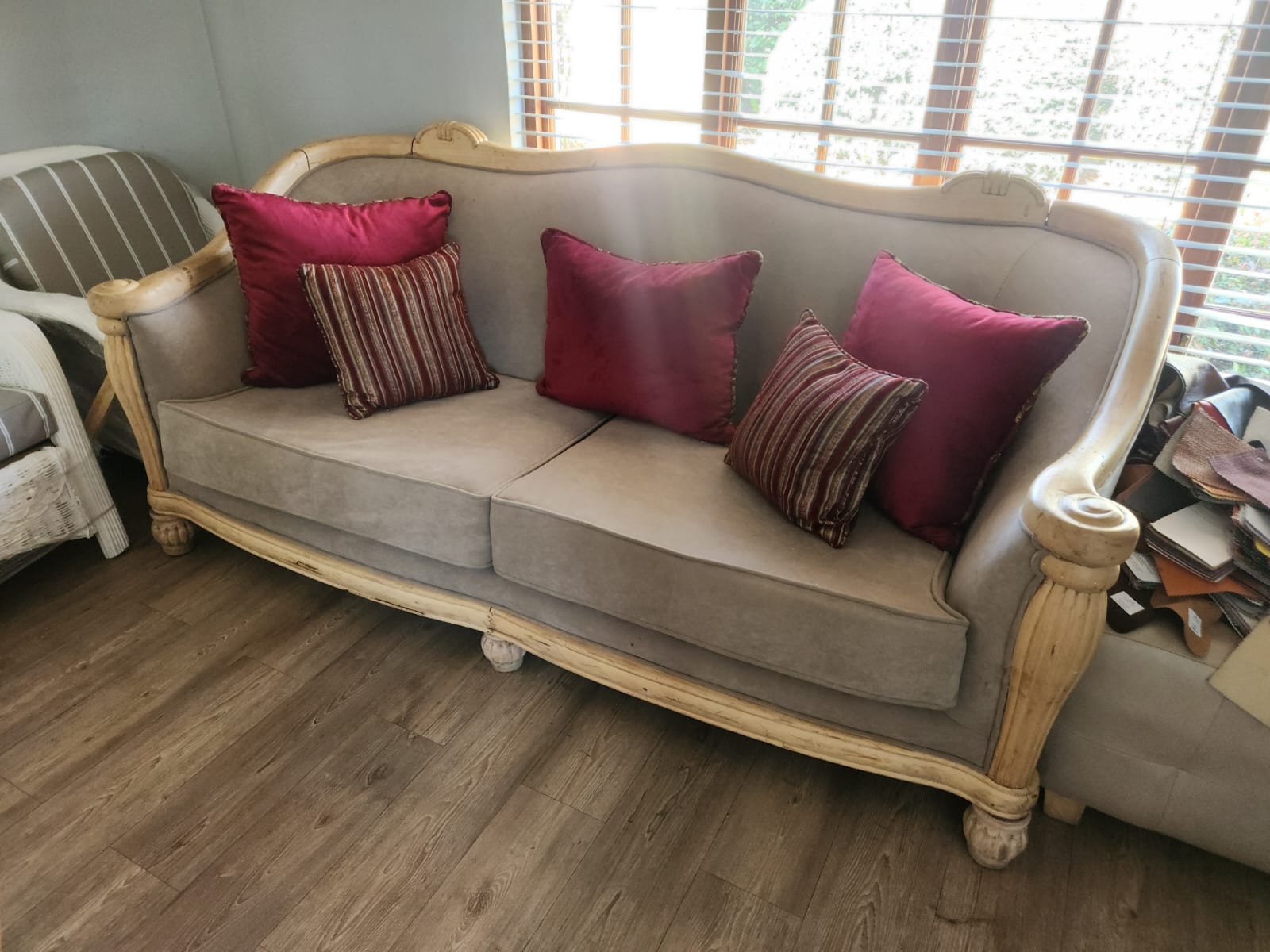 A reupholstered loveseat with maroon scatter cushions in a client's home
